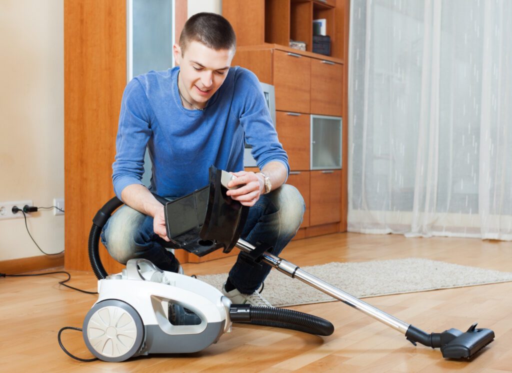 man vacuuming with vacuum cleaner parquet floor living room